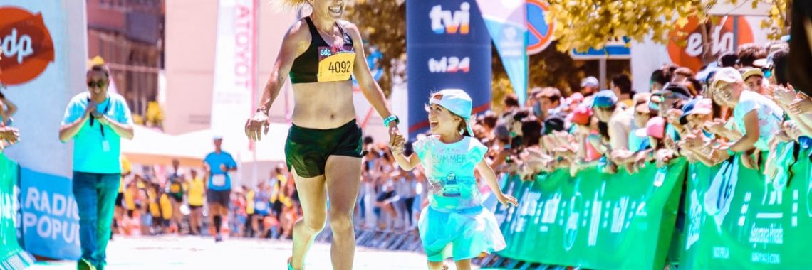 A joyful mother and daughter cross the marathon finish line hand in hand, exuding happiness and energy.